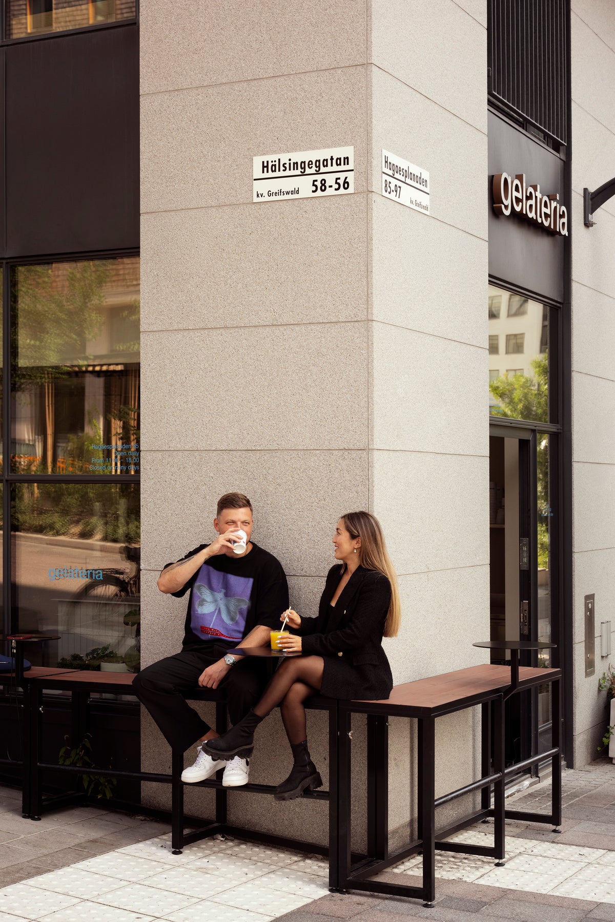 Två personer fikar vid ett litet bord utanför ett café på ett gathörn