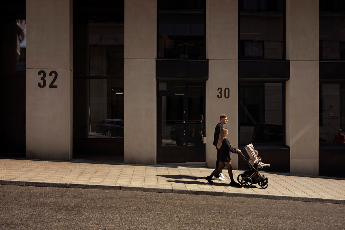 två personer går ner på gatan med ett barnvagn